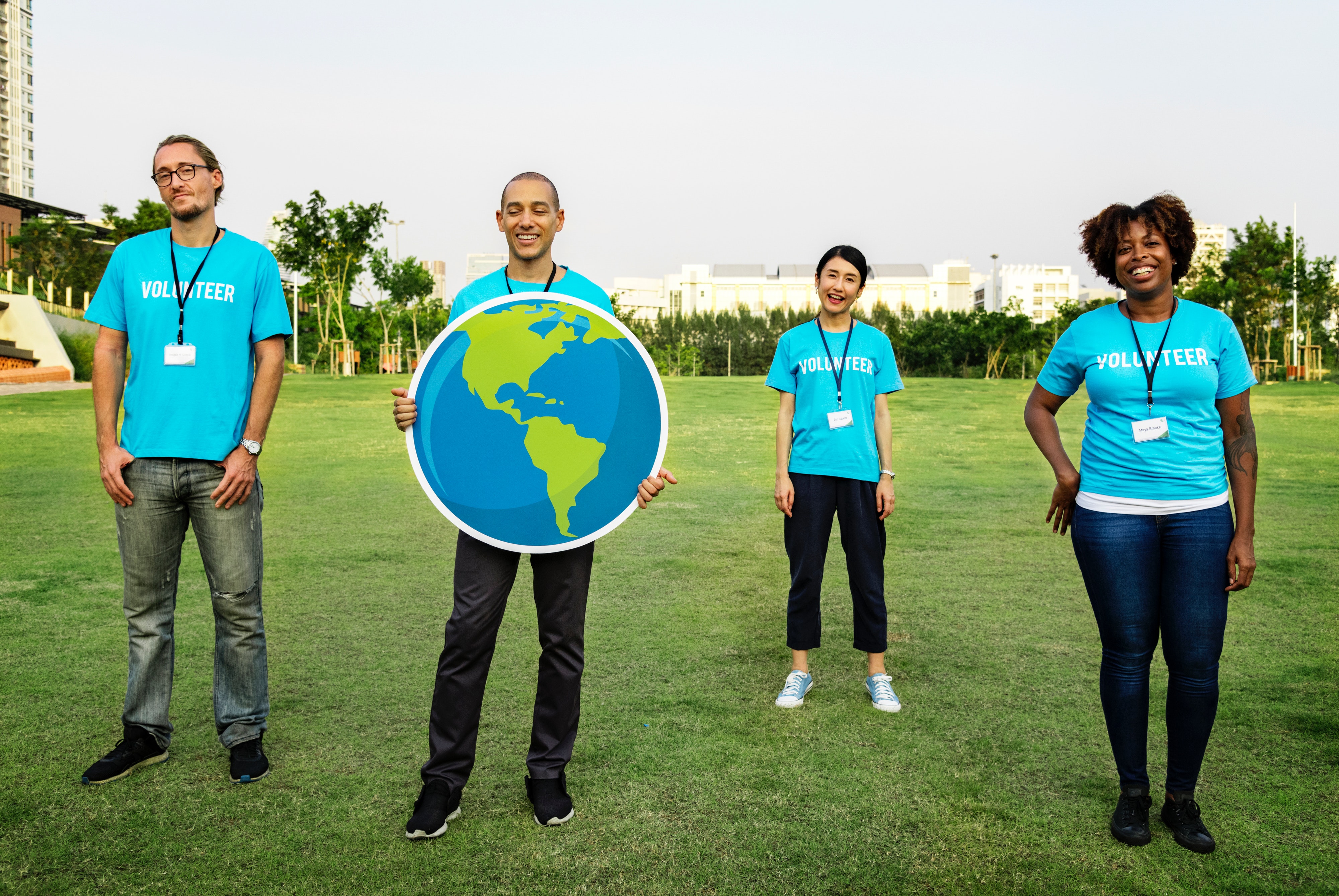 4 persons in blue Shirts outside with world sign