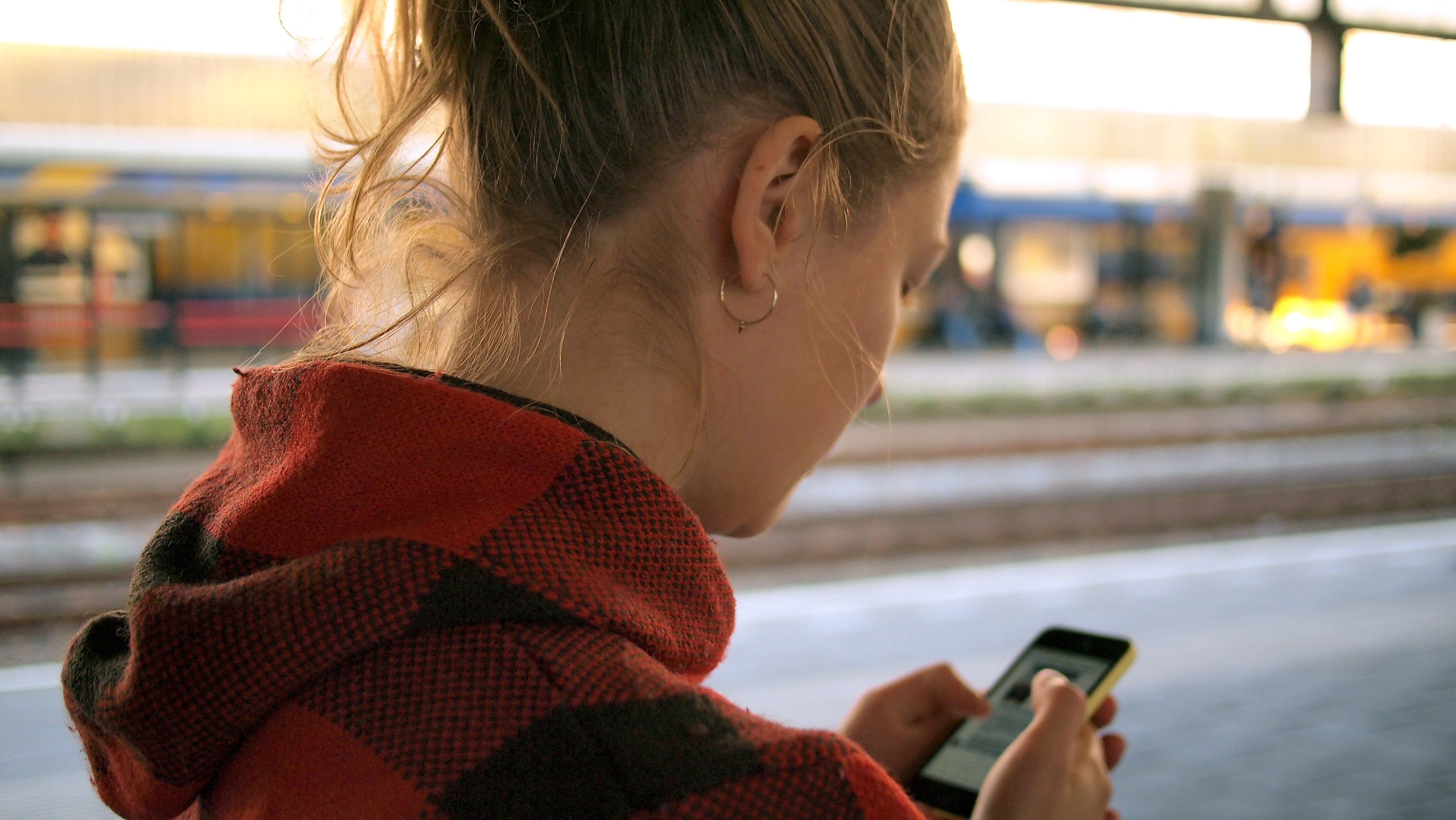 blond woman searching smartphone at trainstation