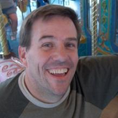 Darren's Profile Picture Darren Overby posing for fun next to pretty ponies on a merry go round