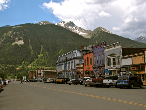 Downtown Silverton Colorado mountains green grass trees street cars traffic buildings town main people walking
