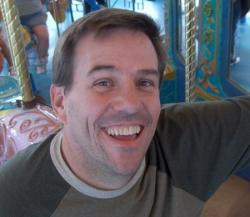 Darren's Profile Picture Darren Overby posing for fun next to pretty ponies on a merry go round