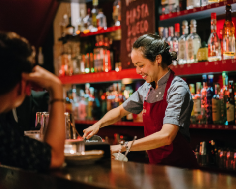 photo of bartender smiling while serving customers